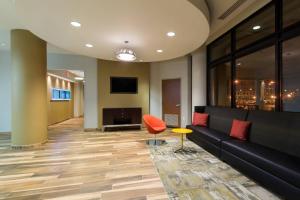 a lobby with a couch and a chair and a television at SpringHill Suites Louisville Downtown in Louisville