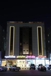 oświetlony budynek z samochodami zaparkowanymi przed nim w obiekcie نيلوفر - Nilover w mieście Tabuk