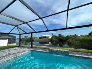 einem Pool mit Glasdach über einem Wasserkörper in der Unterkunft Newly built Villa Ballerina with heated pool and incredible view into beautiful Arrowheadcanal in Cape Coral