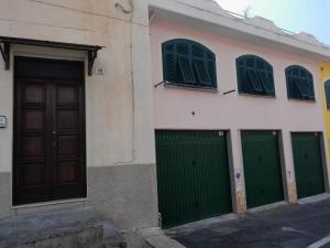 um edifício com portas verdes e janelas numa rua em Bianca's House - since 15/07/23 em Imperia