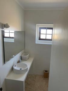 uma casa de banho branca com um lavatório e um espelho em Casa dos Rebolinhos em Sagres