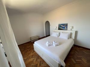 um quarto com uma cama branca com duas toalhas em Casa dos Rebolinhos em Sagres