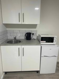 a kitchen with white cabinets and a sink and a microwave at Seven Studio London in London