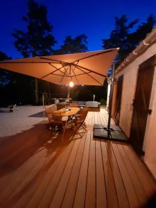 una terraza de madera con una mesa y una sombrilla grande en Les rocailles, en Valderoure