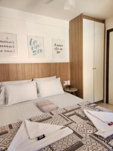 a bedroom with a white bed with towels on it at Genipabu Summer House Guarajuba in Guarajuba