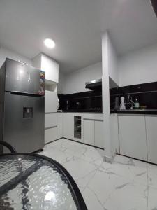 a kitchen with a stainless steel refrigerator and white cabinets at Casa Herrera in Ica