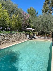 a swimming pool with a table and an umbrella at Rez de jardin de villa avec terrain et piscine in Grasse