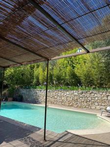 a swimming pool with an umbrella and a stone wall at Rez de jardin de villa avec terrain et piscine in Grasse