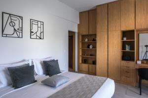 a bedroom with a large white bed and wooden cabinets at Loggia Suites by Good Life in Heraklio