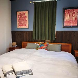 a bedroom with a large white bed with a window at Madarao Mountain Lodge in Iiyama