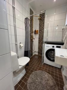 a bathroom with a toilet and a washing machine at Fresh And Cozy Little House 45km In Täby in Stockholm