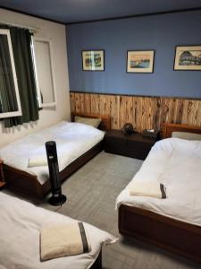 Madarao Mountain Lodge في Iiyama: غرفة نوم بسريرين وجدار ازرق
