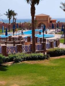 a resort with a pool with tables and palm trees at شاليهات بورتو ساوث بيتش عائلات in Ain Sokhna