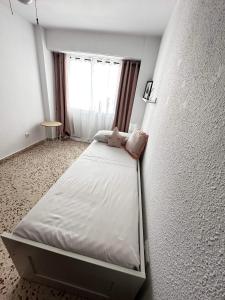 a small bed in a room with a window at Apartamento Mar y Arena in Cullera