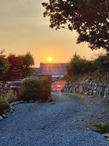 a sunset over a house and a gravel road at Ty Gwennol near Gilfach Goch in Llanbedr