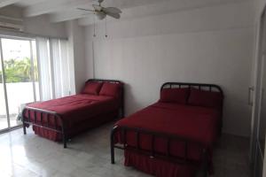 1 dormitorio con 2 camas con sábanas rojas y ventana en Fresca estancia en zona Dorada con Alberca/Playa! en Acapulco