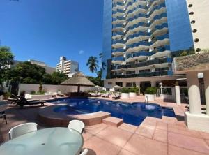 una piscina con sillas y un gran edificio en Fresca estancia en zona Dorada con Alberca/Playa! en Acapulco