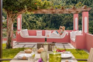 een vrouw zittend op een bank onder een pergola bij Casa do Rosário by An Island Apart in São Vicente