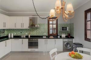 een keuken met witte kasten en een tafel met een fruitschaal bij Casa do Rosário by An Island Apart in São Vicente +34 foto's