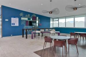 uma cafetaria com mesas e cadeiras e uma parede azul em New Luxury Apartment 12th Floor em San José