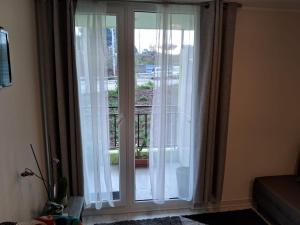 ventana grande con cortinas blancas y balcón en Departamentos Pilmaiquen, en Padre Las Casas