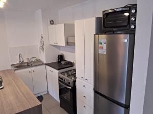 a kitchen with a stainless steel refrigerator and a microwave at Departamentos Pilmaiquen in Padre Las Casas