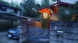 ein Auto, das vor einem Haus mit einem Tor parkt in der Unterkunft Guesthouse Oomiya base 大宮基地別荘 in Chiba