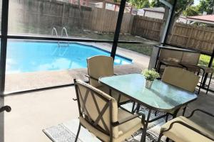 a patio with a table and chairs and a swimming pool at Whole House+Renovated+Pool+Lanai+BBQ+Close to All in West Palm Beach
