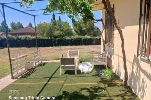 casa rural el mirador في Granja Arenales: فناء مع كرسيين وطاولة على العشب +صورة واحدة
