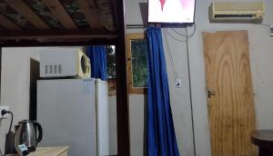 um quarto com um frigorífico, uma televisão e uma porta em Liart Hospedajes em Puerto Iguazú