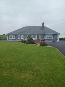 una casa con un césped verde delante de ella en Country Haven eircode H54 AK31 en Galway
