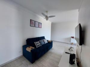 a living room with a blue couch and a flat screen tv at Apartamento Peruíbe in Peruíbe