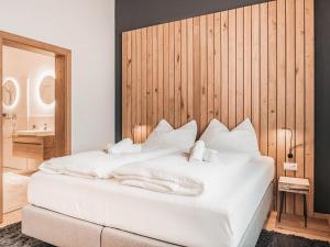 a bedroom with a white bed with a wooden wall at AlpenLuxus' CHEZ NOUS with balcony & car park in Fügen