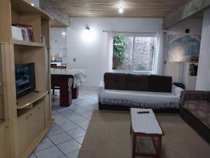 a living room with a couch and a television at Casa a Três Quadras da Praia da Cal! Torres in Torres