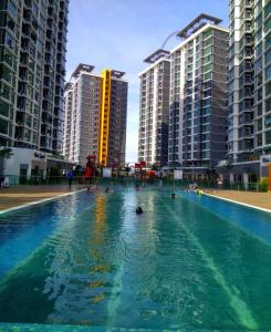 a swimming pool with people in the water with buildings at Rafa Vista Alam Homestay in Shah Alam