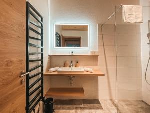 ein Bad mit einem Waschbecken und einem Spiegel in der Unterkunft AlpenLuxus' ZILLERHEART with balcony & car park in Fügen