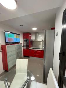 a kitchen with red cabinets and a glass table at APARTAMENTO MODERNO Y ACOGEDOR EN EL CENTRO de ALMERÍA in Almería