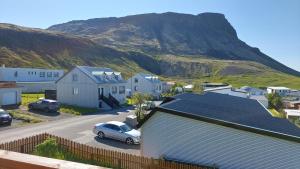 a house with a car parked in front of a mountain at Olafsvik Guesthouse in Ólafsvík