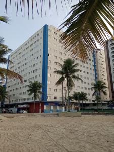 un gran edificio con palmeras delante en Frente ao mar na Praia Grande, en Praia Grande