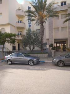 two cars parked in a parking lot in front of a building at Nice inn appartment Lac 2 in El Aouina