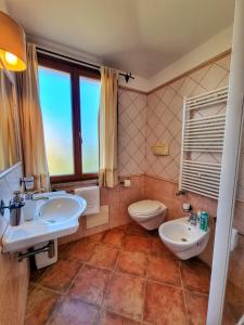 a bathroom with two sinks and a toilet and a window at Domos de Ammentos in Tortolì