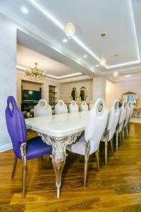 a dining room with a white table and purple chairs at Nizami Street VIP Apartment in Baku