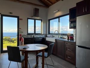 een keuken met een tafel, stoelen en ramen bij A Fonte in Santo António