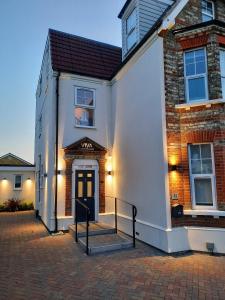 un edificio blanco con una puerta negra y una escalera en Viva Guest House en Clacton-on-Sea