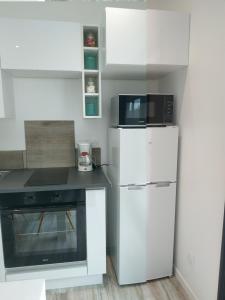 uma cozinha branca com um frigorífico e um micro-ondas em Havre de modernité à la campagne proche Arras em Dainville