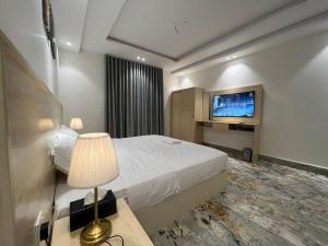 Habitación de hotel con cama y TV de pantalla plana. en سويت إم للأجنحة الفندقية en AR Rummanah
