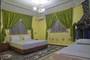 1 dormitorio con 2 camas y cortinas verdes en Riad Dar Fadma en Ouarzazate