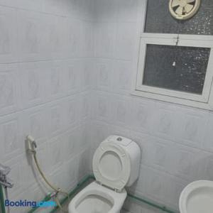 a bathroom with a white toilet and a window at Dormitory bed space in a shared room in Sharjah