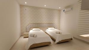 a bedroom with two beds and a sink at Hotel Kai in Uribia
