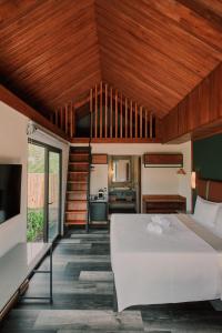 a bedroom with a large white bed and wooden ceilings at Suwa Villa Arenal in Fortuna